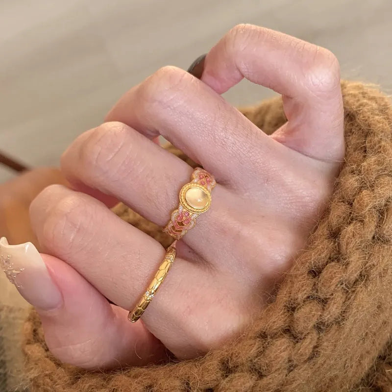A pink crystal enamel ring with a geometric gold-plated copper band and an open mouth adjustable design.