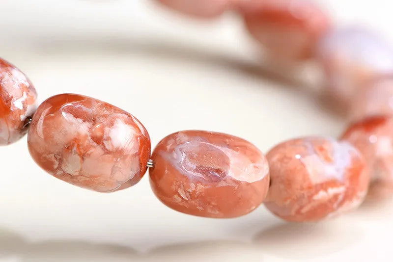 Natural cherry agate bracelet with 10x14mm barrel beads and a geometric ruyi design.