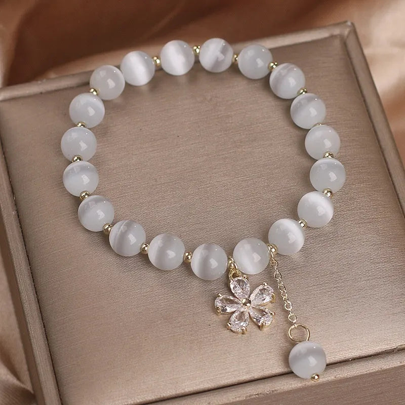 White Cat's Eye stone bracelet with a small flower tassel pendant and a safety buckle.