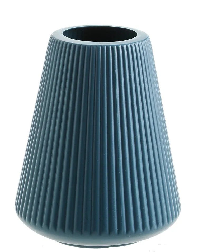 A simple white melamine plastic decorative flower vase on a wooden tabletop.