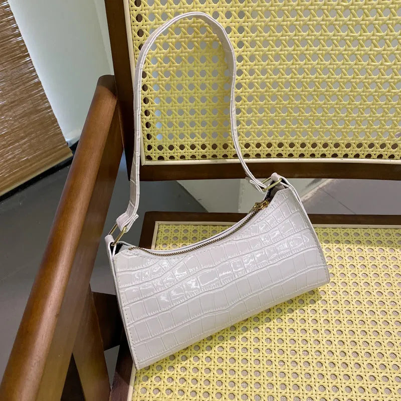 Women's small PU underarm bag with crocodile pattern, belt detail, and zipper closure in beige