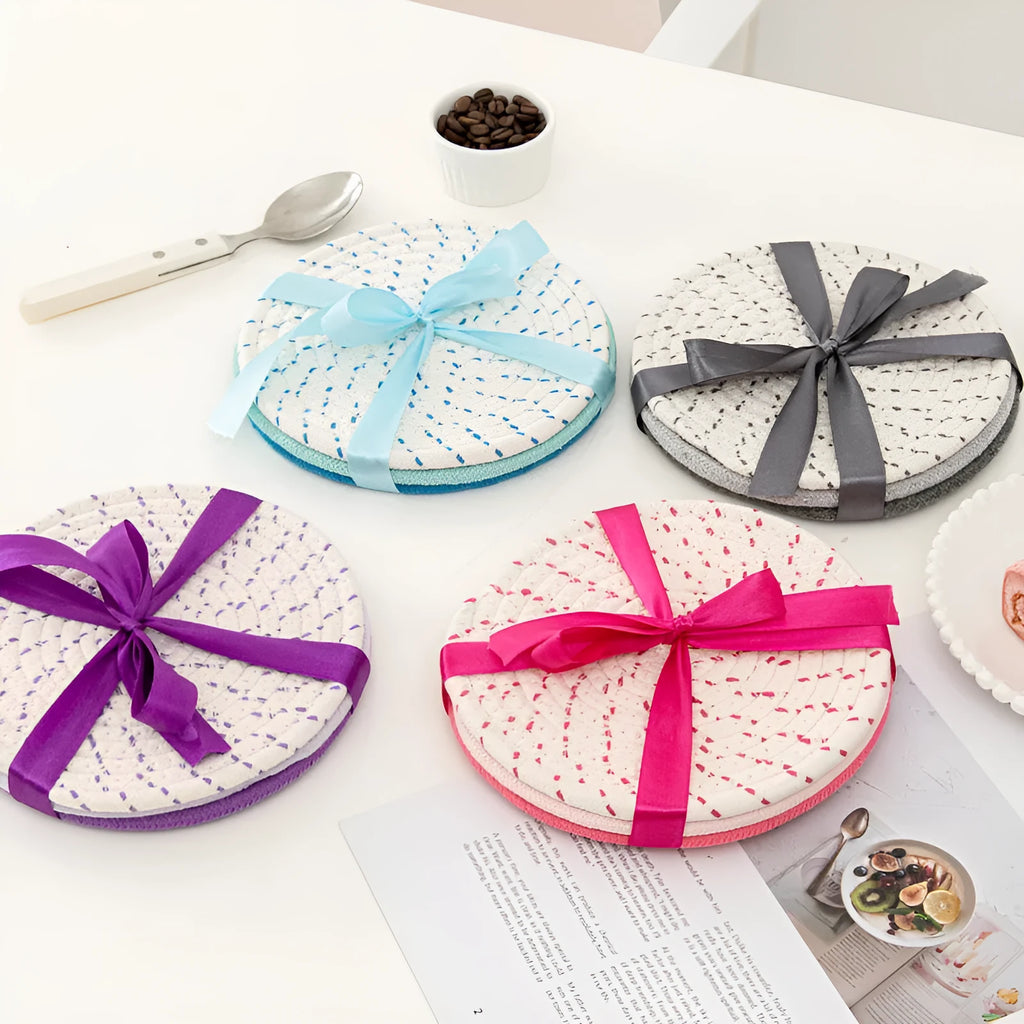 Three round grey cotton cord coasters placed on a wooden table, each 18cm in diameter.