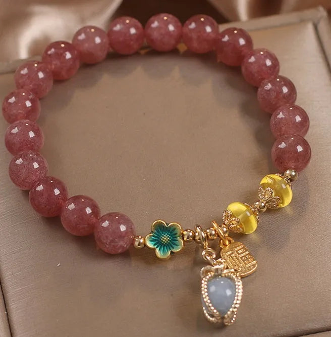 Red bracelet with strawberry quartz beads, alloy metal spacers, and rhinestone decorative details.