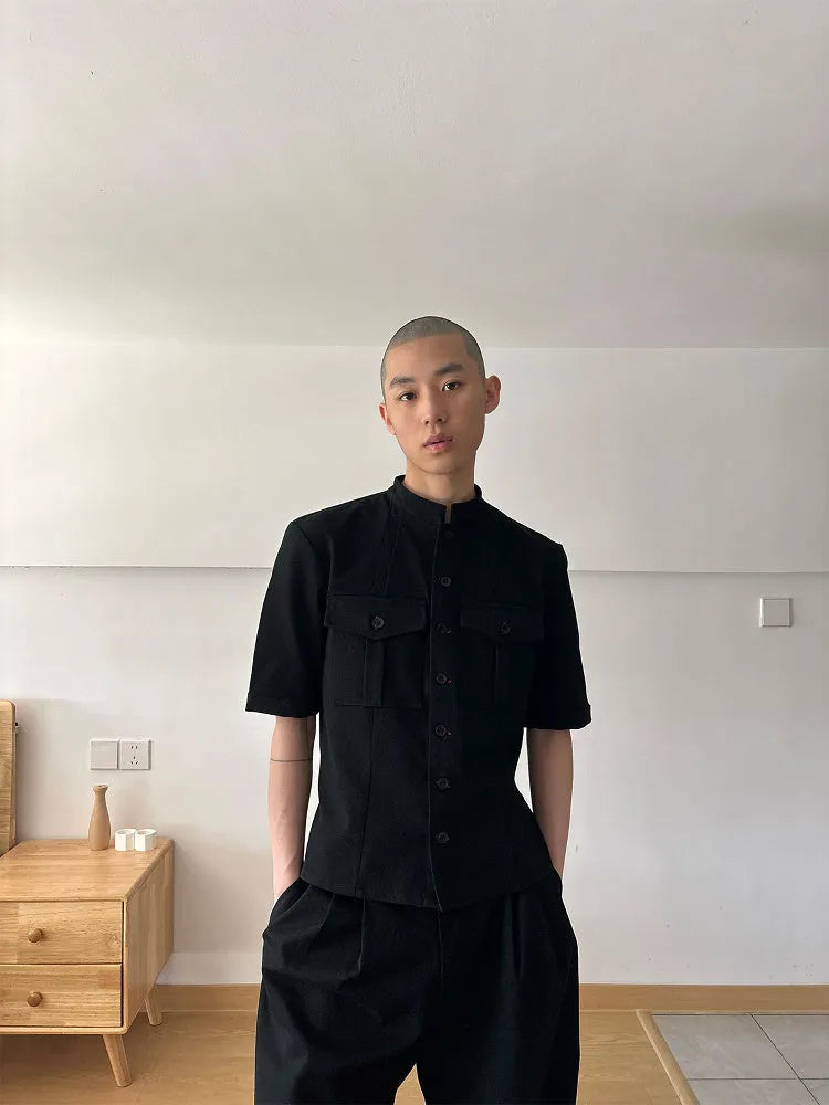 A black handmade half sleeve shirt with a shirt collar, shown on a hanger.