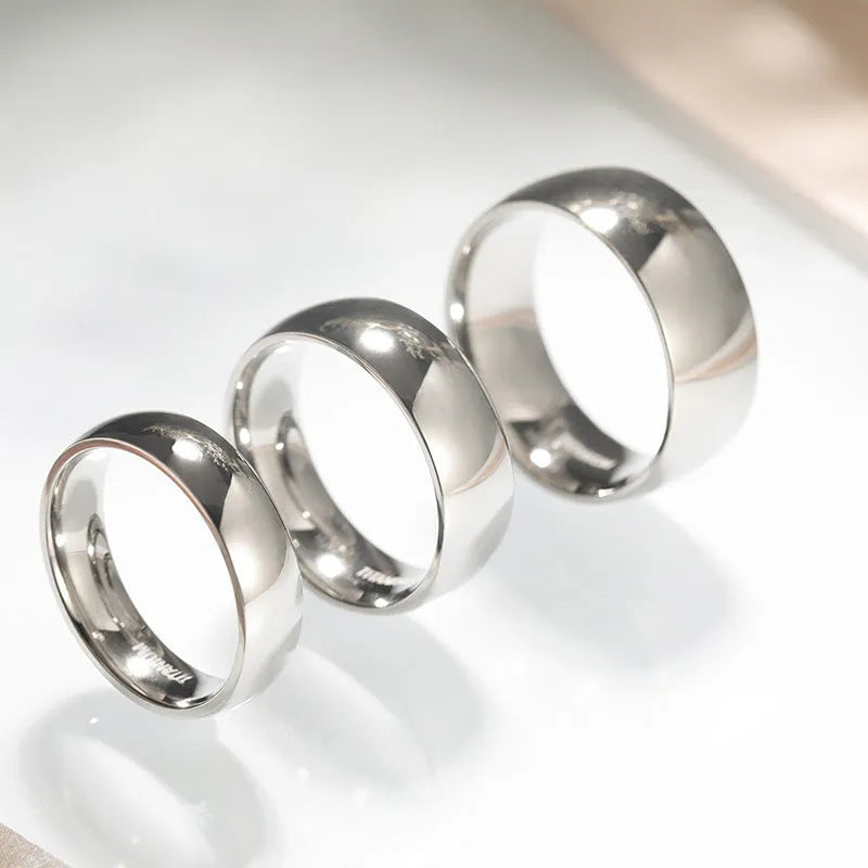 Simple silver-coloured titanium steel band ring with a matte finish on a grey background.