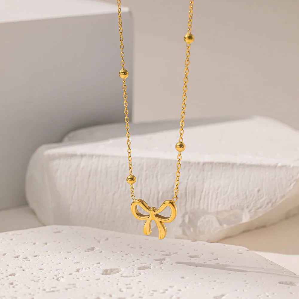 Gold-coloured bow pendant necklace on a cross-link chain, adjustable from 41 to 50 cm.