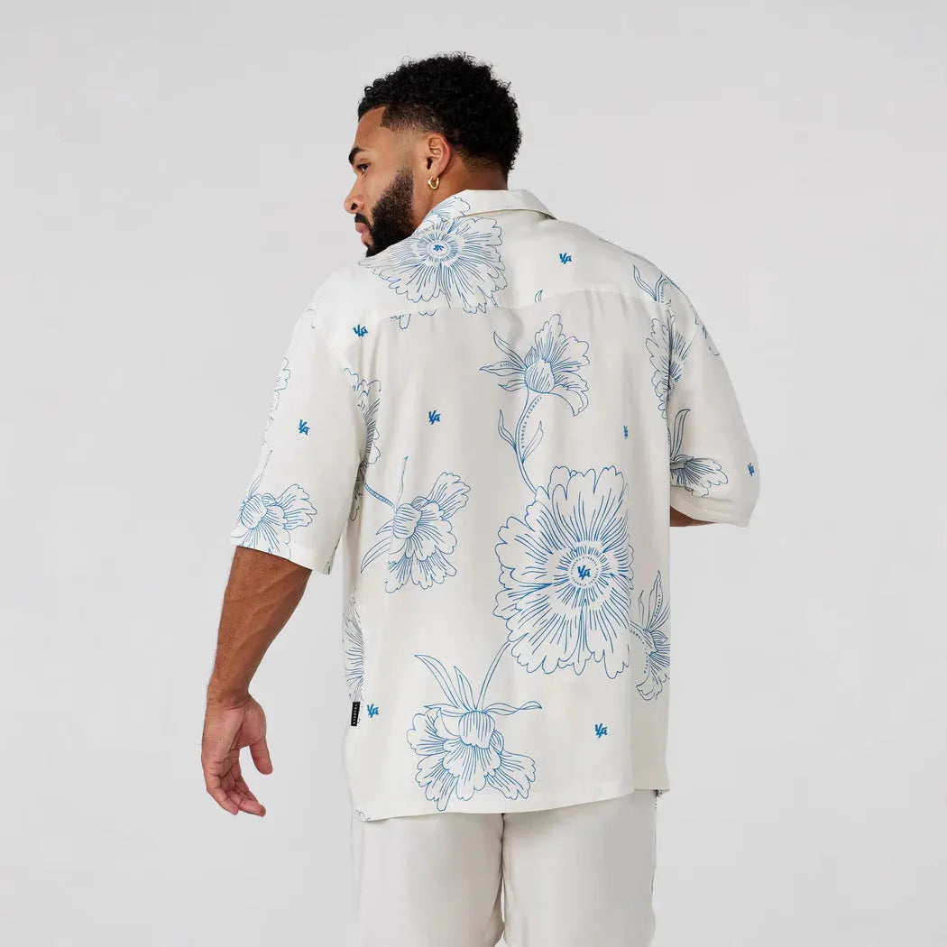 A man modelling a loose-fitting, short-sleeved beige cardigan with a printed floral pattern.