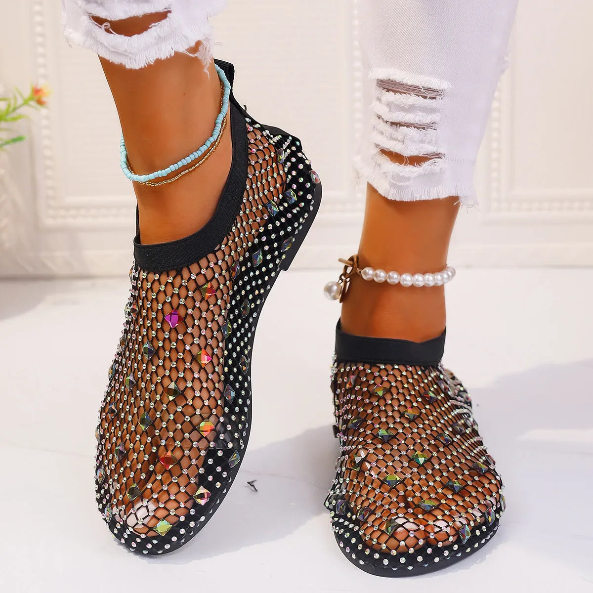 Colourful rhinestone detail on women's white mesh flat sandals with a round toe and rubber sole.