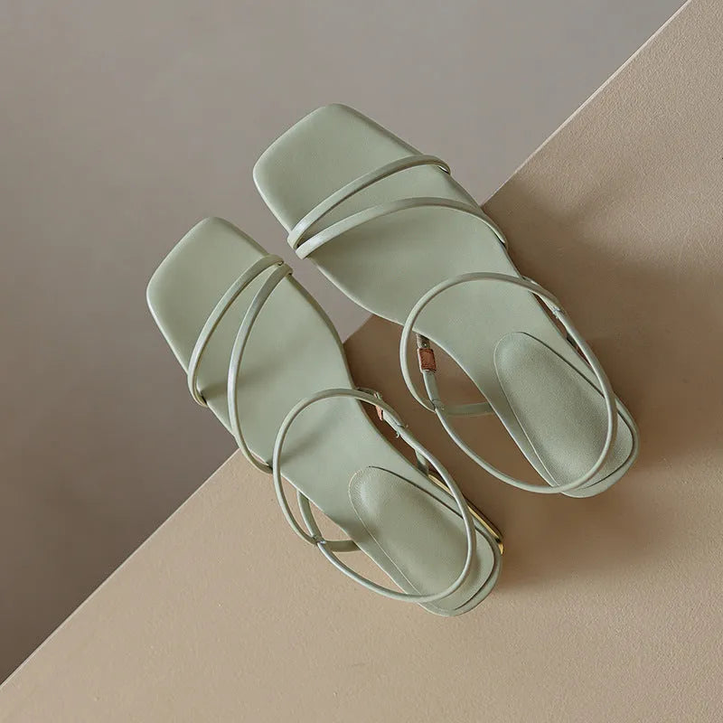 Women's beige flat strap Roman sandals with square open toe on a neutral background