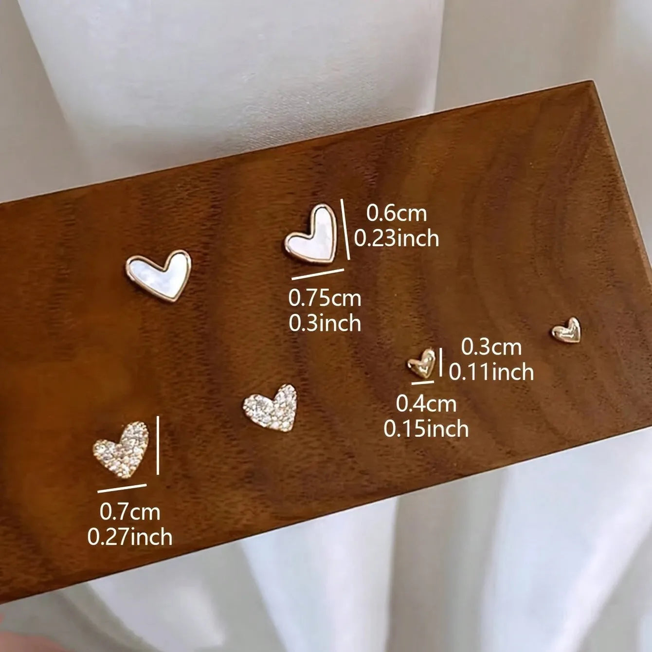 Three pairs of heart-shaped women's earrings in gold, black, and pink colour options