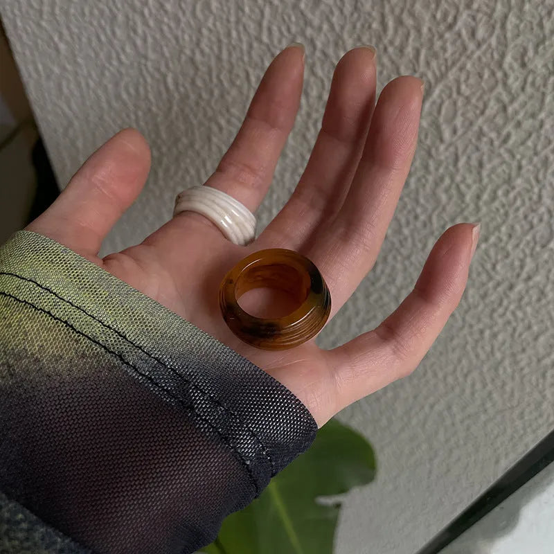 Chinese style irregular geometric wide resin ring in brown or white on a plain background.