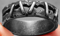 Stainless steel dark punk stitching style double ring on a finger, showing textured design.