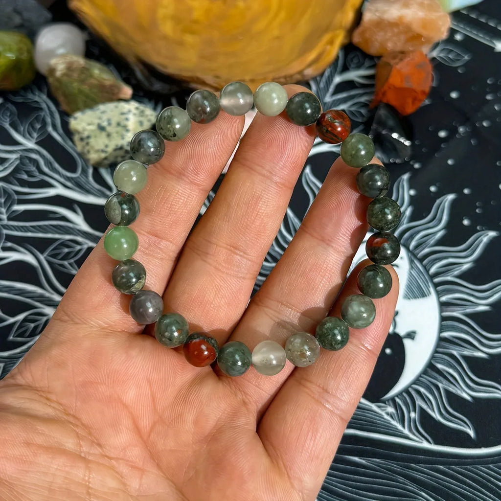 Handmade African Bloodstone beaded bracelet with 8mm transparent glass beads on neutral background