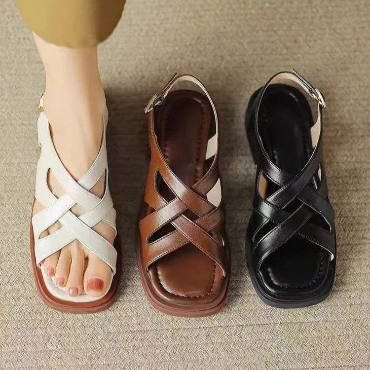 Women's glossy black patent leather sandals with square toe and cross ankle strap.