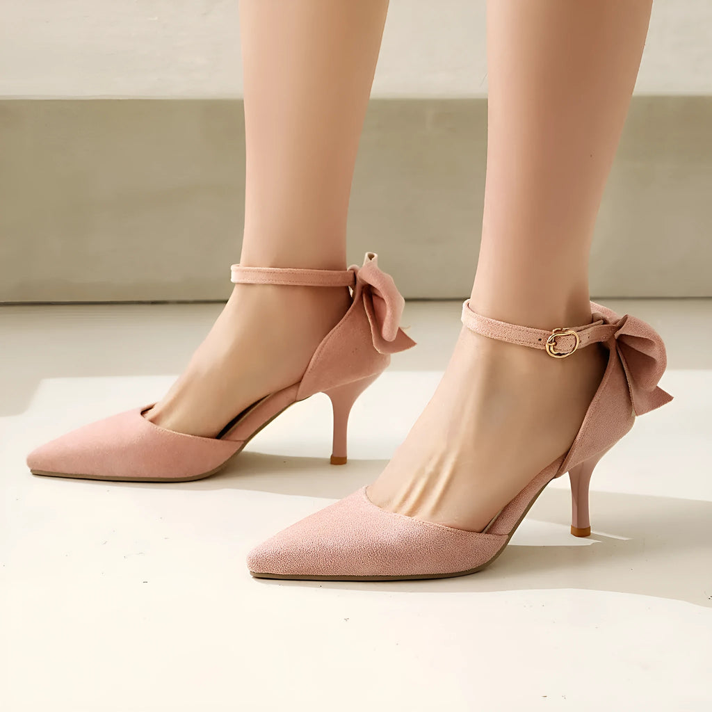 Black suede pointed-toe high heels with a bowknot and stiletto heel on a white background.
