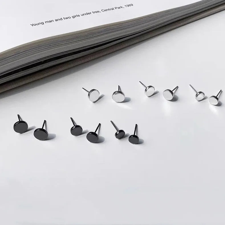 A pair of S999 sterling silver geometric round flat ear bone studs in black and silver finishes, showing size scale.