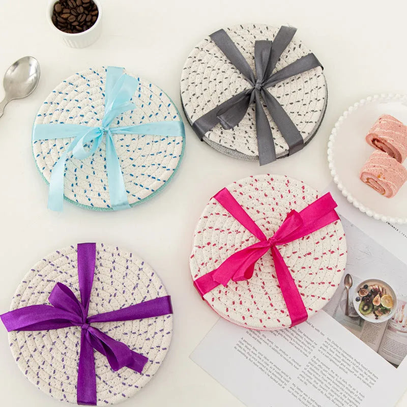 Three round grey cotton cord coasters placed on a wooden table, each 18cm in diameter.