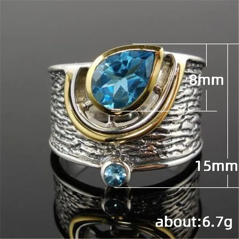 Blue zircon drop-shaped ring with Chinese style rhinestone inlay, shown on a finger.