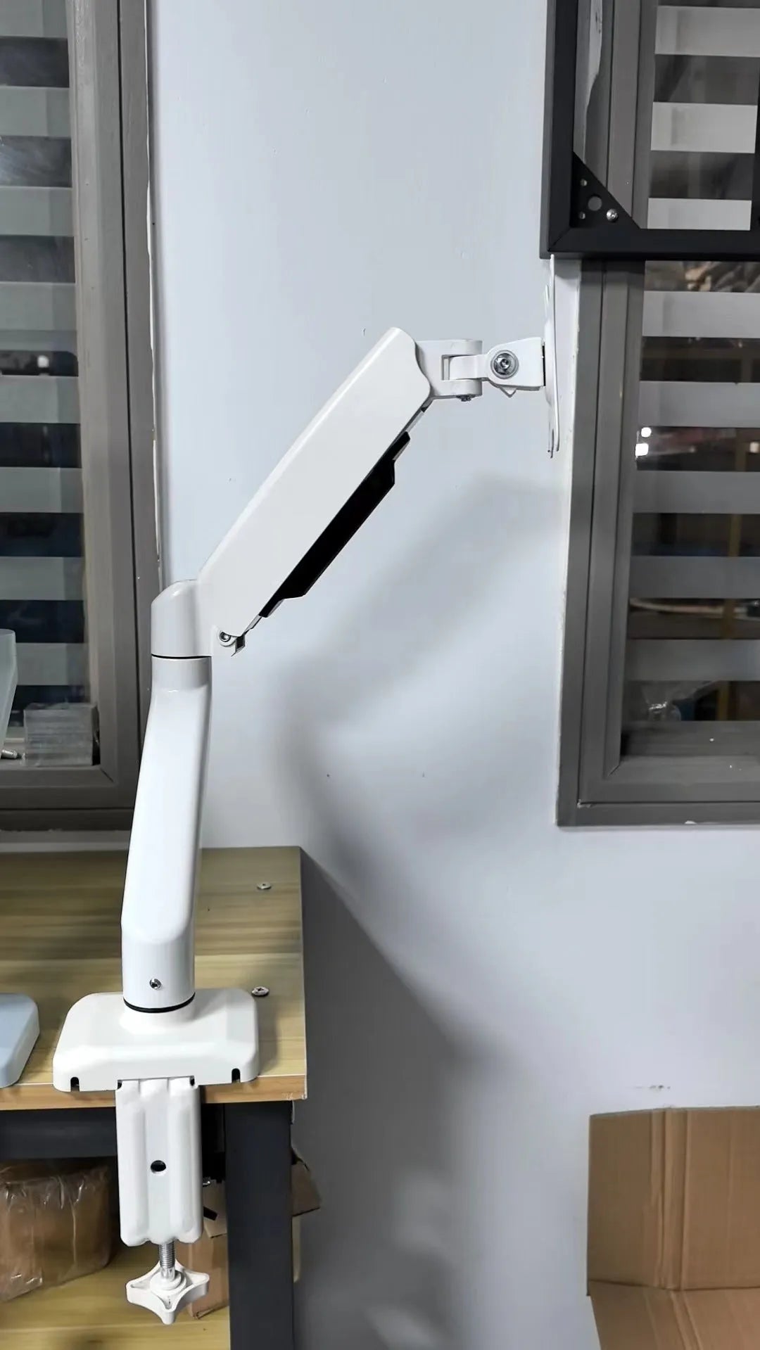 Black rotating telescopic LCD screen bracket elevated on table with monitor