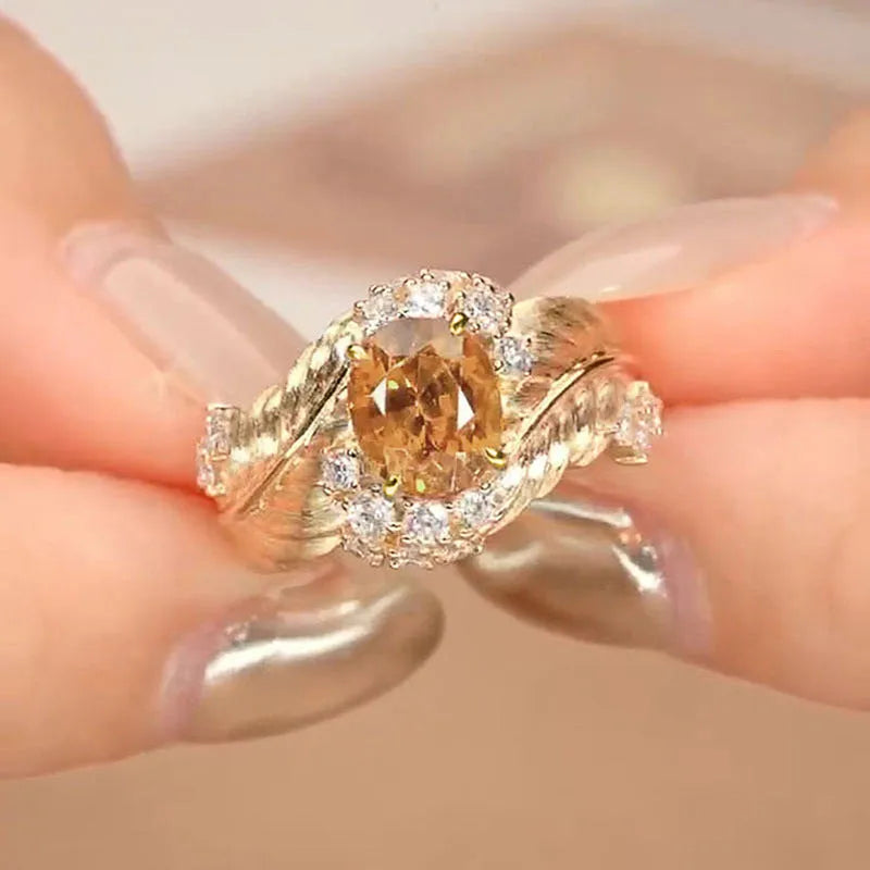 Gold-toned copper women's ring with an embossed feather design and a central yellow zircon stone.
