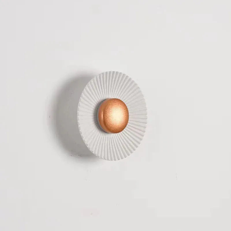 Round wall lamp with aluminium shade in a two-tone white and gold colour combination, mounted on a plain wall.