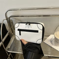 A dark grey women's square crossbody bag made of PU leather, shown with a single shoulder strap and visible sewing line detail.