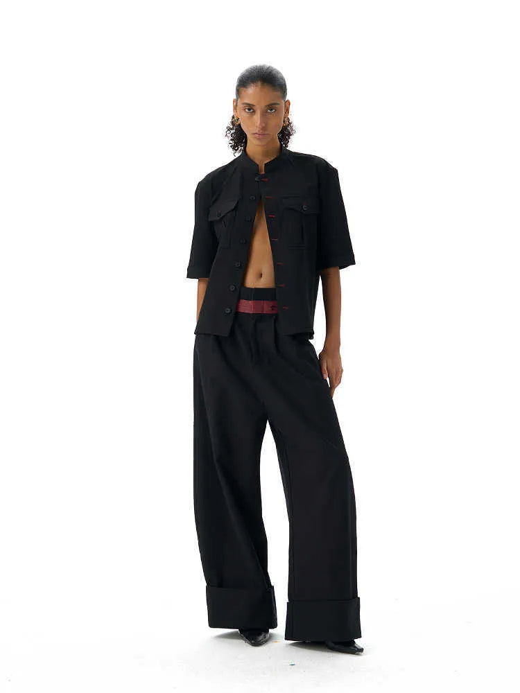A black handmade half sleeve shirt with a shirt collar, shown on a hanger.
