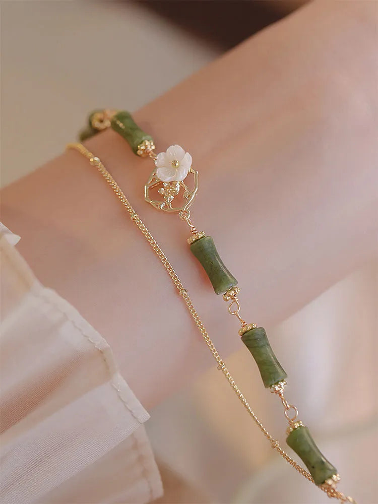 A green olivine stone bracelet with double layers, an Olive Branch charm, and Twin Bells of Ireland pendant.