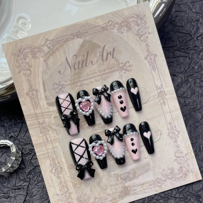 Handmade black and pink heart-shaped false nails with Cat's Eye, Bow, and XINGX hand-painted designs.