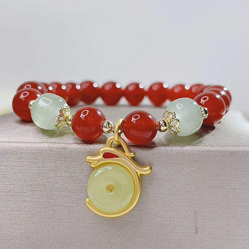 Close-up of a red agate bracelet with a Chinese dragon design on a woman's wrist.